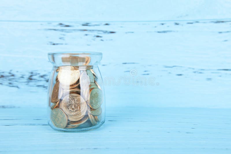 Glazen spaarpot tegen blauwe achtergrond stock fotografie