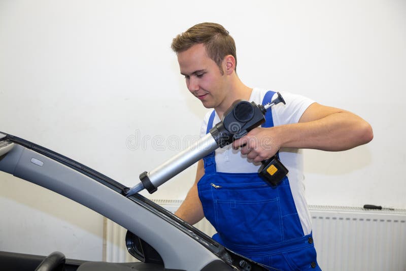 Glazier with Application Gun Applying Adhesive for Windshield