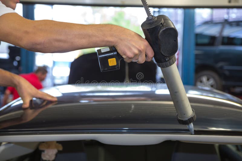 Glazier with Application Gun Applying Adhesive for Windshield
