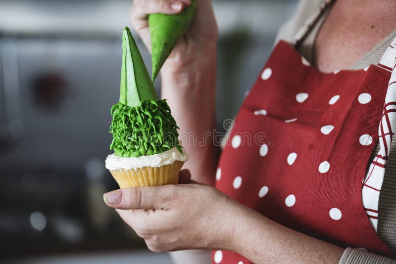 Glaçage sifflant de Baker sur un petit gâteau photographie stock Glaçage sifflant de Baker sur un petit gâteau photographie stock