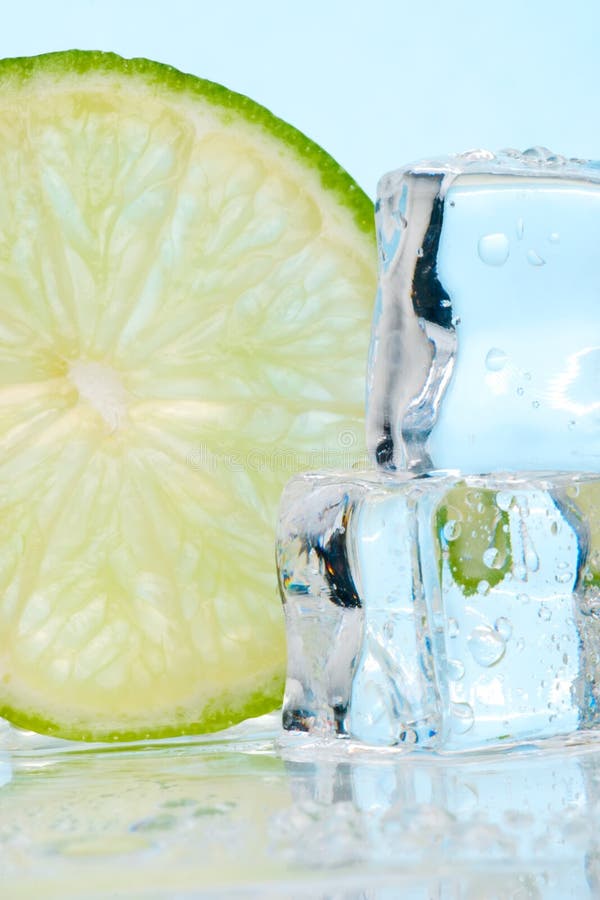 Two stacked ice cubes melted in water and slice of lime on reflection surface ready to be added to a cocktail. Two stacked ice cubes melted in water and slice of lime on reflection surface ready to be added to a cocktail