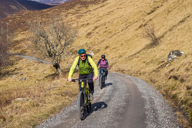 22.03.22 Glen Tilt, Perthshire, Scotland, Two cyclists one in green, one in purple cycle down one of the main tracks in Glen Tilt. 22.03.22 Glen Tilt, Perthshire, Scotland, Two cyclists one in green, one in purple cycle down one of the main tracks in Glen Tilt