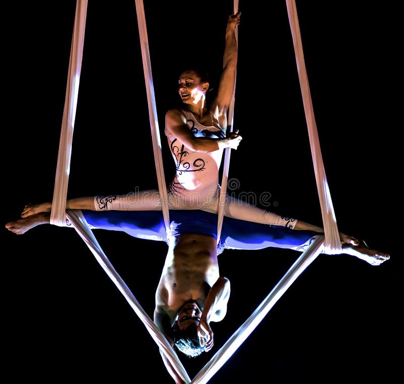 Gli acrobate eseguono un trucco sulle imbracature hanno sospeso la i. Bitonto, Italia - 28 maggio 2017: Gli acrobate eseguono un trucco sulle imbracature sospese nel vuoto ed hanno fissato con i cablaggi su una sera festiva nel quadrato principale di Bitonto, Puglia