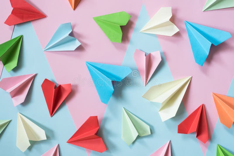 Gli aeroplani di carta variopinti sul rosa pastello e sul blu hanno colorato il fondo immagini stock libere da diritti Gli aeroplani di carta variopinti sul rosa pastello e sul blu hanno colorato il fondo immagini stock libere da diritti