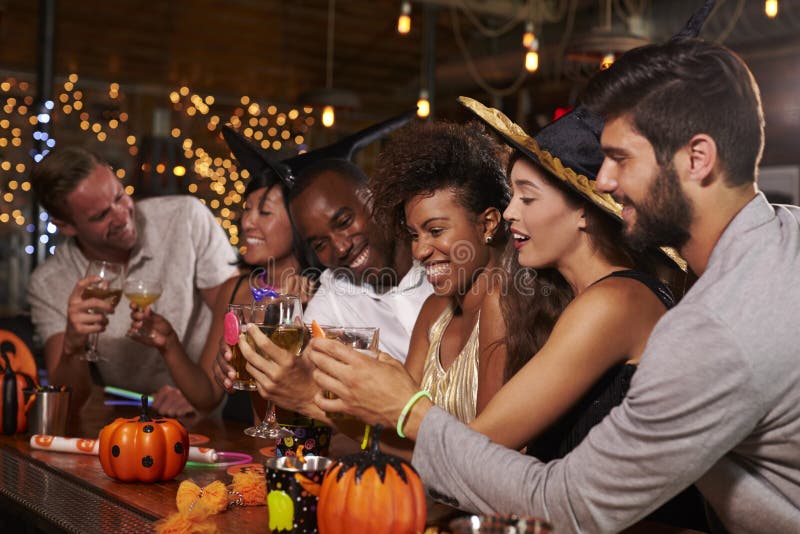 Gli amici che godono di un Halloween fanno festa ad una barra che produce un pane tostato immagine stock libera da diritti Gli amici che godono di un Halloween fanno festa ad una barra che produce un pane tostato immagine stock libera da diritti