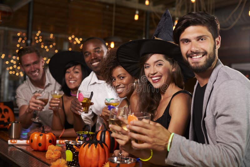 Gli amici che godono di un partito di Halloween ad una barra guardano alla macchina fotografica fotografia stock libera da diritti Gli amici che godono di un partito di Halloween ad una barra guardano alla macchina fotografica fotografia stock libera da diritti