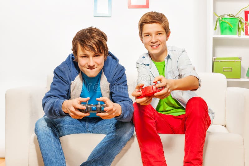 Gli amici felici tengono le leve di comando e la console del gioco del gioco immagine stock libera da diritti Gli amici felici tengono le leve di comando e la console del gioco del gioco immagine stock libera da diritti