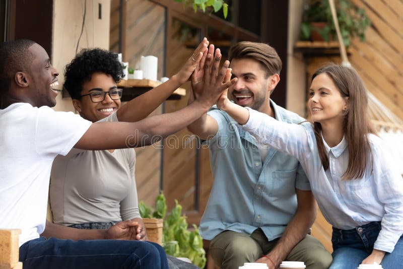 Gli amici multietnici felici che danno su cinque, celebrano il successo immagini stock Gli amici multietnici felici che danno su cinque, celebrano il successo immagini stock