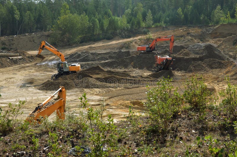 Excavators are developing a sand pit. Extracted gravel and sand for road construction. Excavators are developing a sand pit. Extracted gravel and sand for road construction.