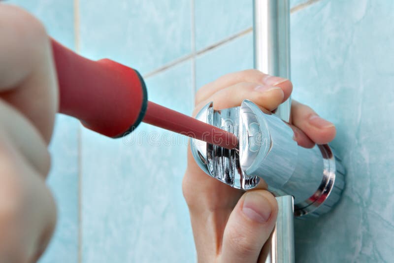 Residential plumbing repair, close-up of hands handyman with red phillips screwdriver, install adjustable shower slide rail bar bracket. Residential plumbing repair, close-up of hands handyman with red phillips screwdriver, install adjustable shower slide rail bar bracket.