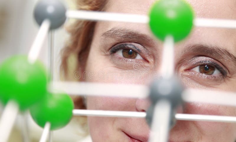 Image of a female researcher eye through a molecular model structure.Selective focus on the eye. Image of a female researcher eye through a molecular model structure.Selective focus on the eye.