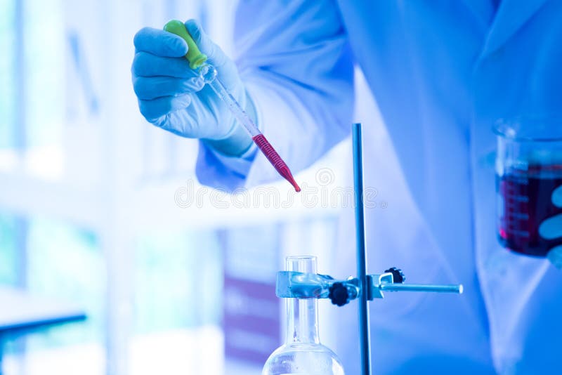 Gli scienziati cadono il liquido nella provetta nel tono blu del laboratorio fotografia stock libera da diritti Gli scienziati cadono il liquido nella provetta nel tono blu del laboratorio fotografia stock libera da diritti