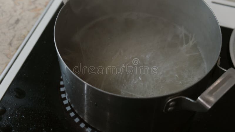 Gli spaghetti del riso stanno cucinando in un vaso di acqua bollente sulla stufa Vista laterale