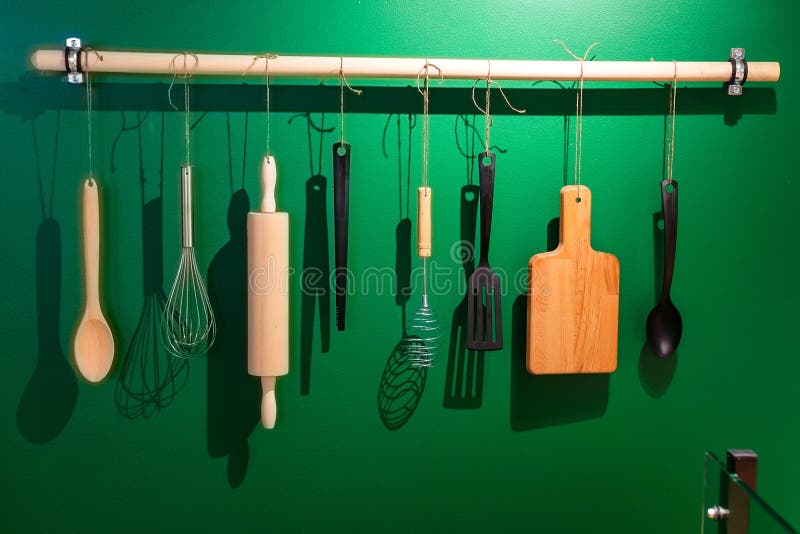Gli strumenti di legno e di plastica della cucina appendono sui ganci fotografie stock Gli strumenti di legno e di plastica della cucina appendono sui ganci fotografie stock