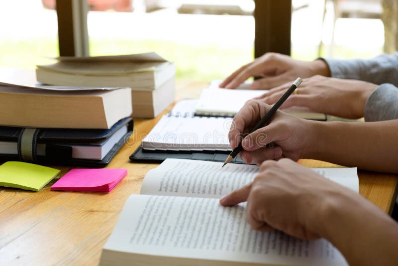 Gli studenti aiuta l'amico che insegna e che impara a supplementare tematico in biblioteca facendo uso della compressa all'istruz fotografia stock Gli studenti aiuta l'amico che insegna e che impara a supplementare tematico in biblioteca facendo uso della compressa all'istruz fotografia stock