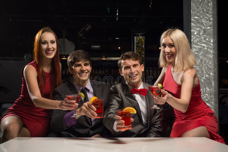Gli uomini e le donne hanno alzato i loro vetri con i cocktail immagini stock Gli uomini e le donne hanno alzato i loro vetri con i cocktail immagini stock