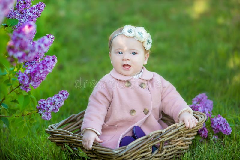 Glimlachend babymeisje 1-2 éénjarigen die bloemkroon dragen, die boeket van sering in openlucht houden het bekijken camera de tij stock afbeelding Glimlachend babymeisje 1-2 éénjarigen die bloemkroon dragen, die boeket van sering in openlucht houden het bekijken camera de tij stock afbeelding