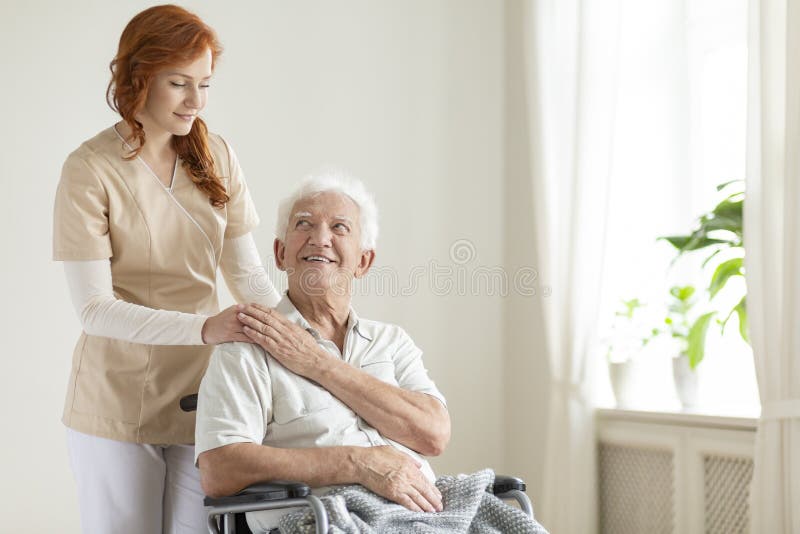 Smiling elderly men in a wheelchair and friendly caregiver in a nursing house. Smiling elderly men in a wheelchair and friendly caregiver in a nursing house