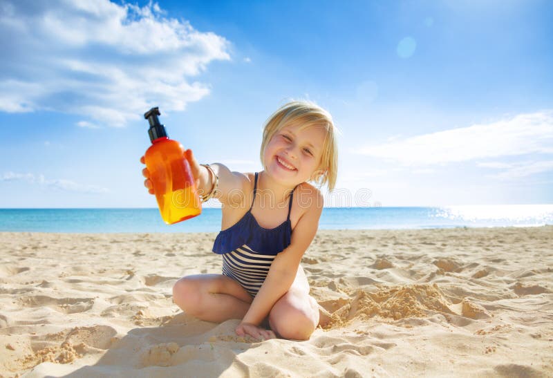 Glimlachend gezond kind in swimwear op zeekust die lotion tonen royalty-vrije stock foto's Glimlachend gezond kind in swimwear op zeekust die lotion tonen royalty-vrije stock foto's