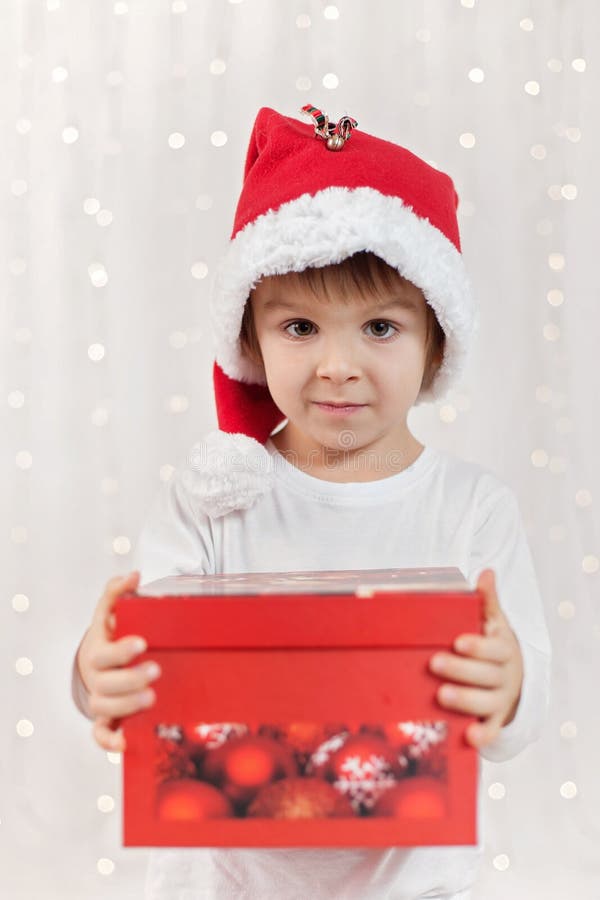 Glimlachend grappig kind in gift van de holdingskerstmis van de Kerstman de rode hoed in h stock afbeelding Glimlachend grappig kind in gift van de holdingskerstmis van de Kerstman de rode hoed in h stock afbeelding