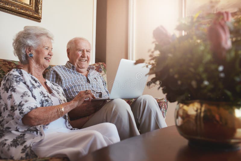 Glimlachend hoger paar die laptop thuis met behulp van royalty-vrije stock foto's Glimlachend hoger paar die laptop thuis met behulp van royalty-vrije stock foto's