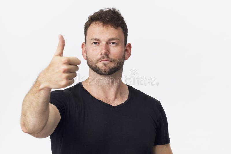 Glimlachend positief mannetje die met aantrekkelijke blik, zwarte t-shirt dragen, die tegen witte blinde muur stellen stock foto's Glimlachend positief mannetje die met aantrekkelijke blik, zwarte t-shirt dragen, die tegen witte blinde muur stellen stock foto's