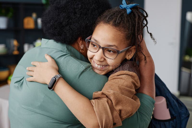 Portrait of smiling African American girl embracing grandmother at home visiting family. Portrait of smiling African American girl embracing grandmother at home visiting family