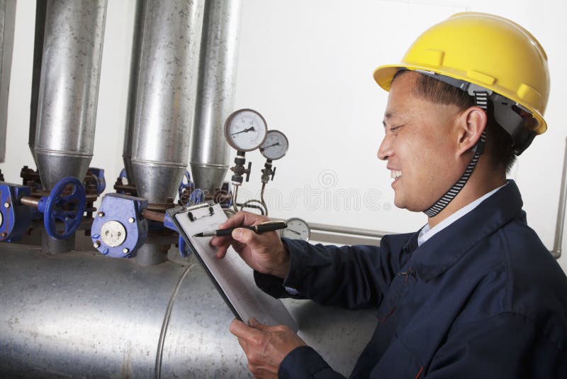 Glimlachende arbeider die het materiaal van de oliepijpleiding in een gasinstallatie controleren, Peking, China royalty-vrije stock afbeelding Glimlachende arbeider die het materiaal van de oliepijpleiding in een gasinstallatie controleren, Peking, China royalty-vrije stock afbeelding
