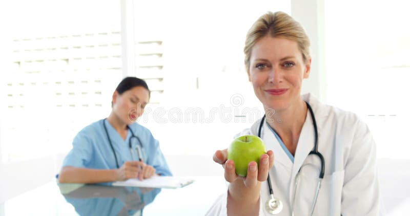 Glimlachende arts die een groene appel tonen