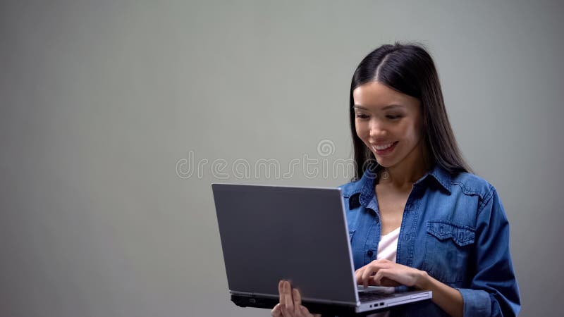 Glimlachende Aziatische vrouw die op laptop babbelen, die met vrienden, nieuwe app communiceren royalty-vrije stock afbeeldingen Glimlachende Aziatische vrouw die op laptop babbelen, die met vrienden, nieuwe app communiceren royalty-vrije stock afbeeldingen
