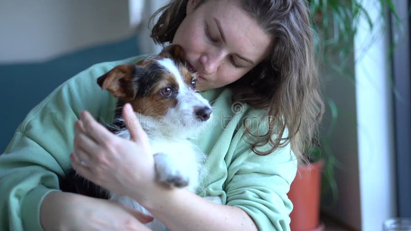 Glimlachende caucasiaanse vrouw die haar hond kust en knuffelt en thuis op de grond zit. gezelschapsdieren voor lifestyle en