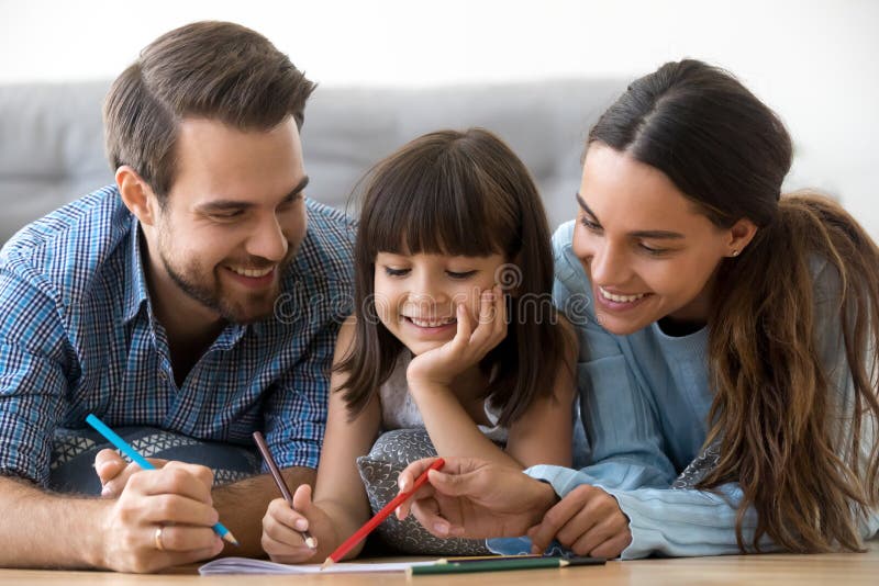 Glimlachende gevende ouders en de leuke tekening van de kinddochter met penc royalty-vrije stock fotografie Glimlachende gevende ouders en de leuke tekening van de kinddochter met penc royalty-vrije stock fotografie