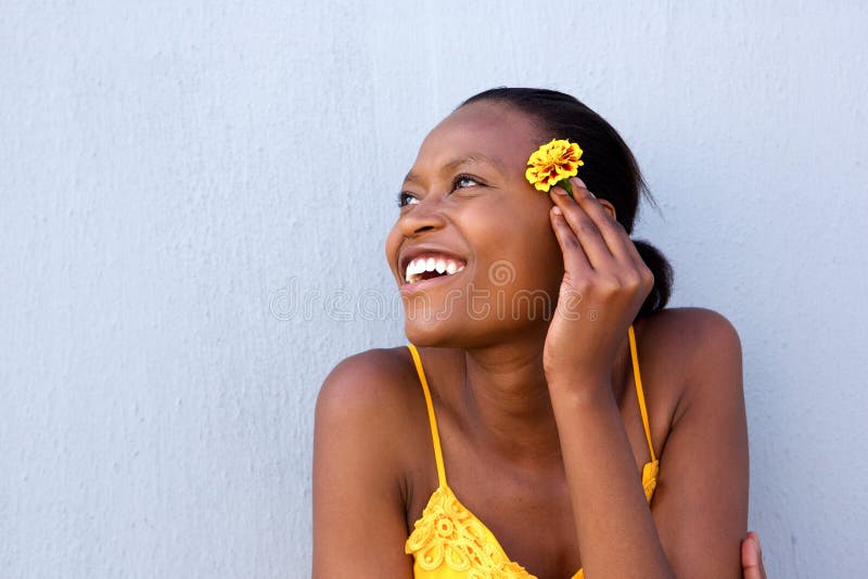 Close up portrait of smiling young african lady holding a flower and looking away. Close up portrait of smiling young african lady holding a flower and looking away