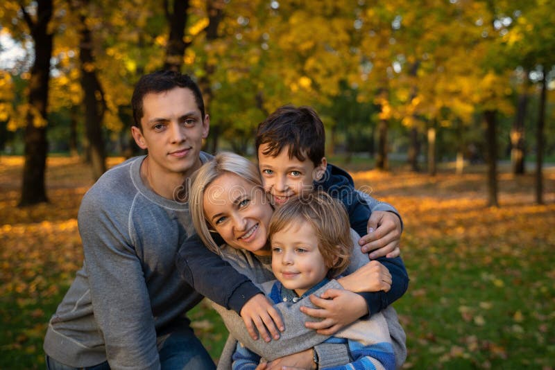 Glimlachende jonge familie in bladeren op een de herfstdag royalty-vrije stock afbeelding Glimlachende jonge familie in bladeren op een de herfstdag royalty-vrije stock afbeelding