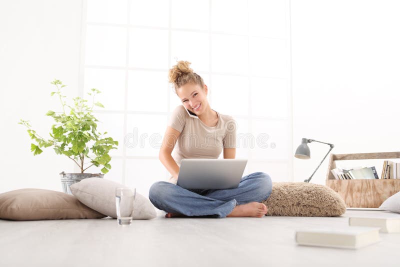 Glimlachende jonge vrouw met computerbespreking op de celtelefoon, sittin stock fotografie Glimlachende jonge vrouw met computerbespreking op de celtelefoon, sittin stock fotografie