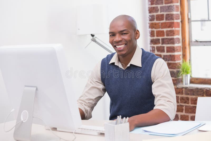 Glimlachende jonge zakenman met computer bij bureau stock fotografie Glimlachende jonge zakenman met computer bij bureau stock fotografie