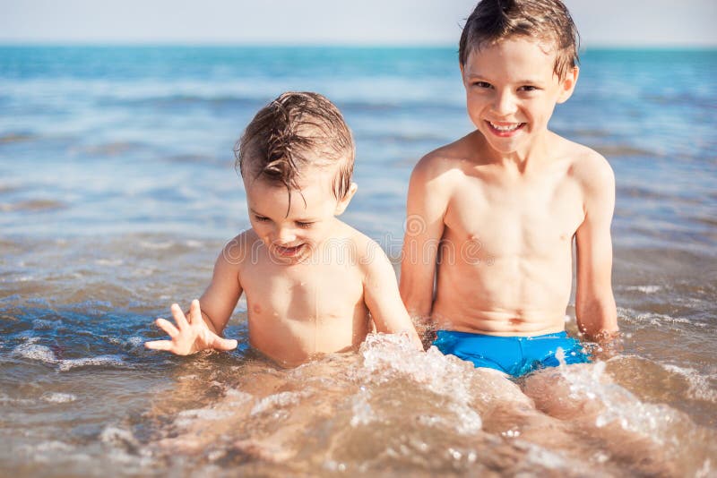 Glimlachende jongens die op strand zitten royalty-vrije stock foto's Glimlachende jongens die op strand zitten royalty-vrije stock foto's