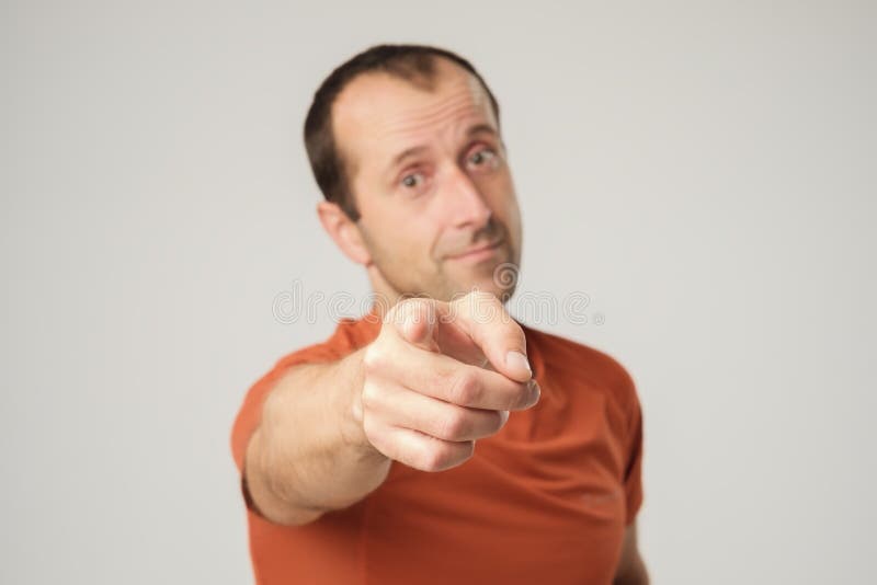 Glimlachende Kaukasische mens die in oranje t-shirt vinger richten op u stock foto's Glimlachende Kaukasische mens die in oranje t-shirt vinger richten op u stock foto's