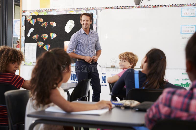 Glimlachende leraar bij voorzijde van basisschoolklasse stock fotografie Glimlachende leraar bij voorzijde van basisschoolklasse stock fotografie
