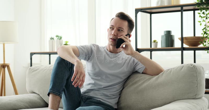 Glimlachende man die aan het telefoongesprek op de bank deelneemt