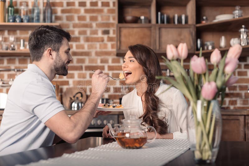 Glimlachende man voedende vrouw met cake in keuken royalty-vrije stock fotografie Glimlachende man voedende vrouw met cake in keuken royalty-vrije stock fotografie
