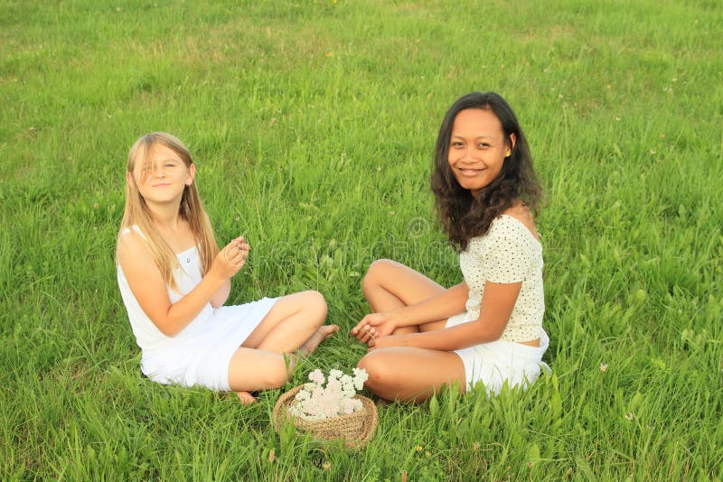 Glimlachende meisjes die op gras zitten