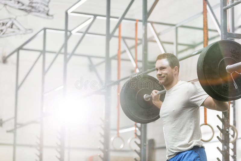 Glimlachende mens die barbell bij crossfitgymnastiek opheffen royalty-vrije stock afbeeldingen Glimlachende mens die barbell bij crossfitgymnastiek opheffen royalty-vrije stock afbeeldingen