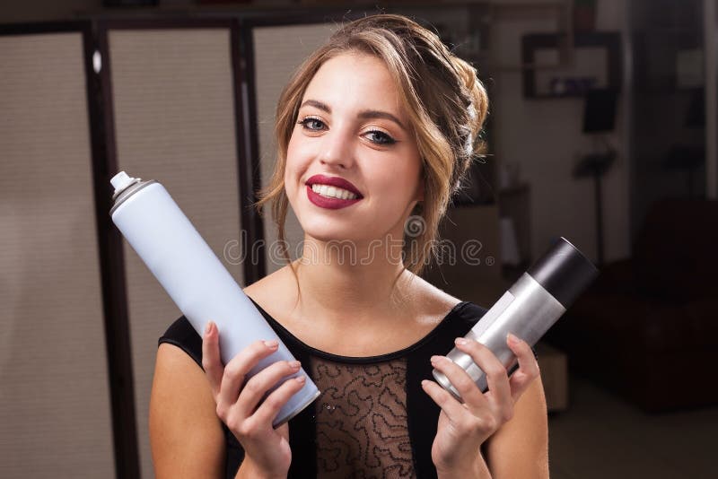 Glimlachende modelholding twee haarlakken royalty-vrije stock afbeelding Glimlachende modelholding twee haarlakken royalty-vrije stock afbeelding