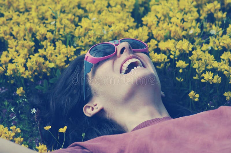 Glimlachende vrouw die met zonnebril op een weidehoogtepunt leggen met yello royalty-vrije stock afbeelding Glimlachende vrouw die met zonnebril op een weidehoogtepunt leggen met yello royalty-vrije stock afbeelding