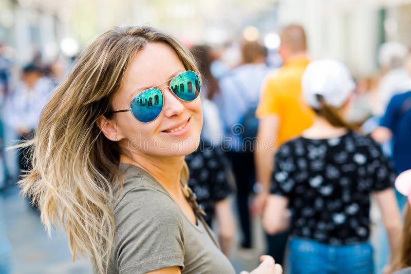Glimlachende vrouw die in zonglazen terug in een stad kijken stock foto Glimlachende vrouw die in zonglazen terug in een stad kijken stock foto