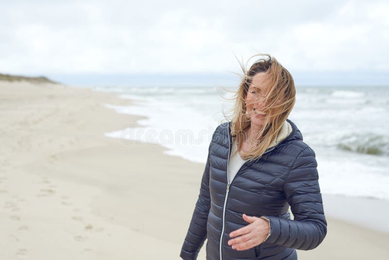 Glimlachende vrouw op het winderige verlaten strand lachen royalty-vrije stock foto's Glimlachende vrouw op het winderige verlaten strand lachen royalty-vrije stock foto's