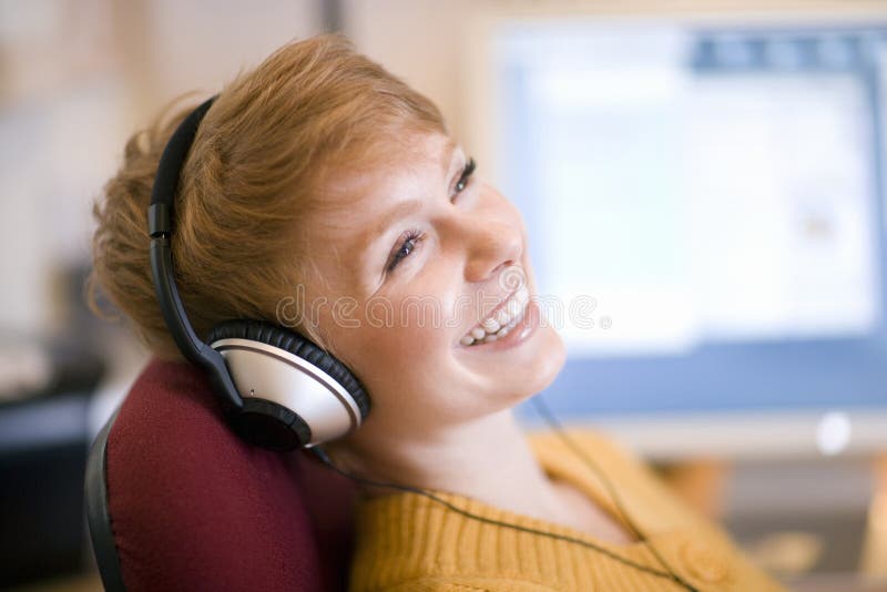 Young laughing woman relaxing in chair listening to headphones. Young laughing woman relaxing in chair listening to headphones