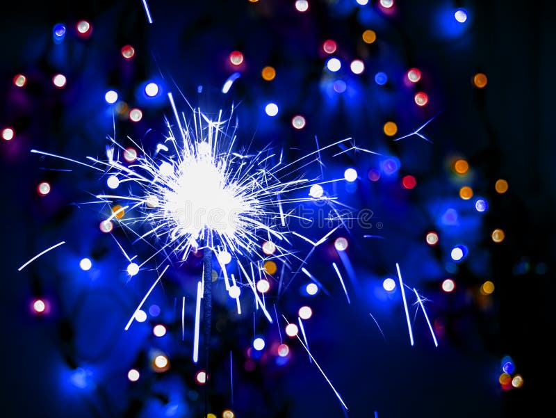 Glittering Burning Sparkler on Colorful Bokeh Background. Stock Photo