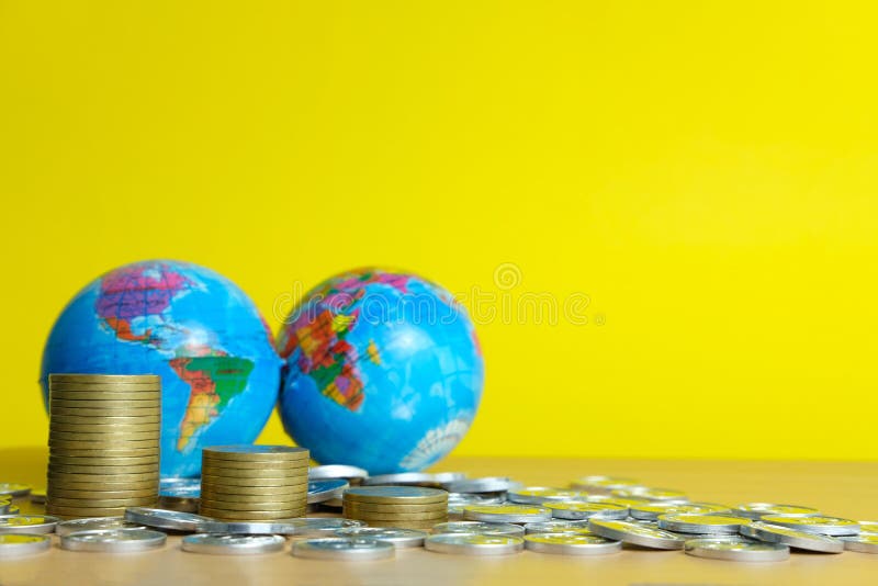Global trade and financial concept - decreasing stack of coin in front of earth globe